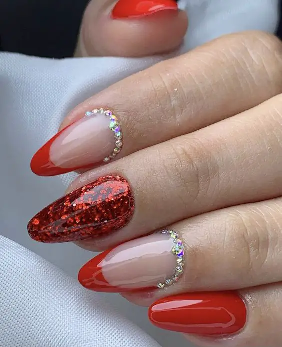 Modelo de unhas lindas vermelhas com glitter e joias de unhas