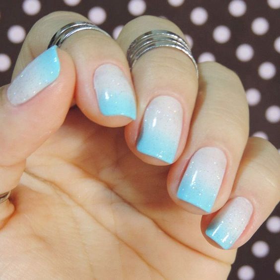 Modelo de unhas curtas decoradas com esmalte azul e branco