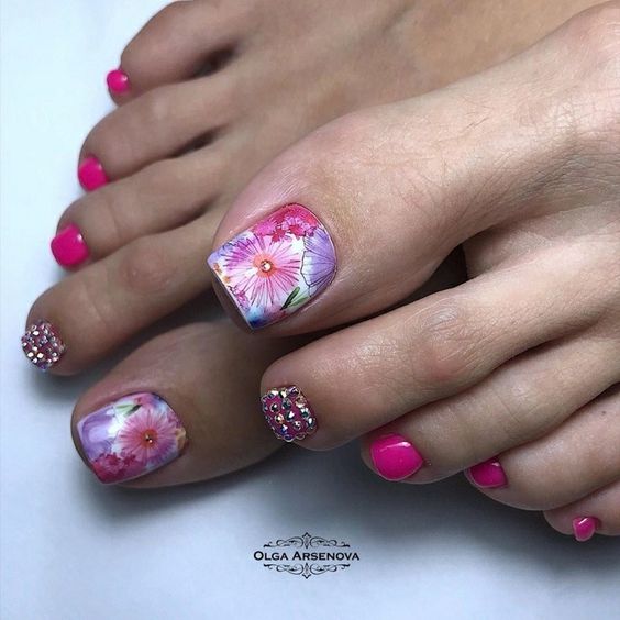 unhas cor de rosa intensa com flores no dedo maior do pé e jóias