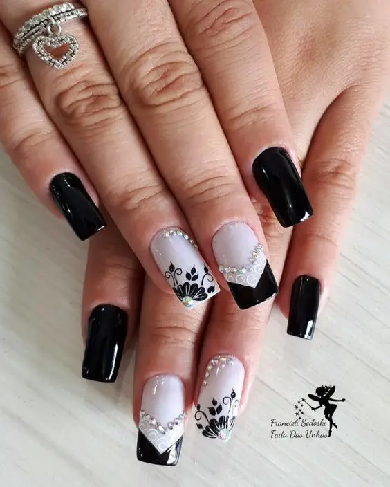 combinação de unhas pretas e brancas com desenhos florais e joias