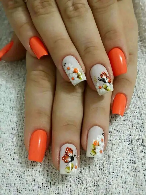 unhas laranjas decoradas com adesivos de flores
