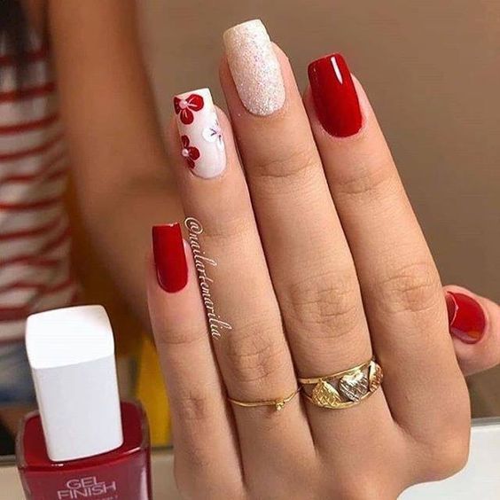 unhas esmaltadas de vermelho com decorações brancas