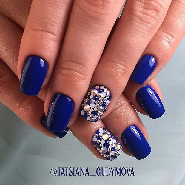 unhas pintadas de azul vibrante decoradas com pedras brilhantes
