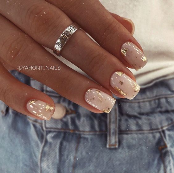 unhas feitas com esmalte branco decoradas com folhas de ouro