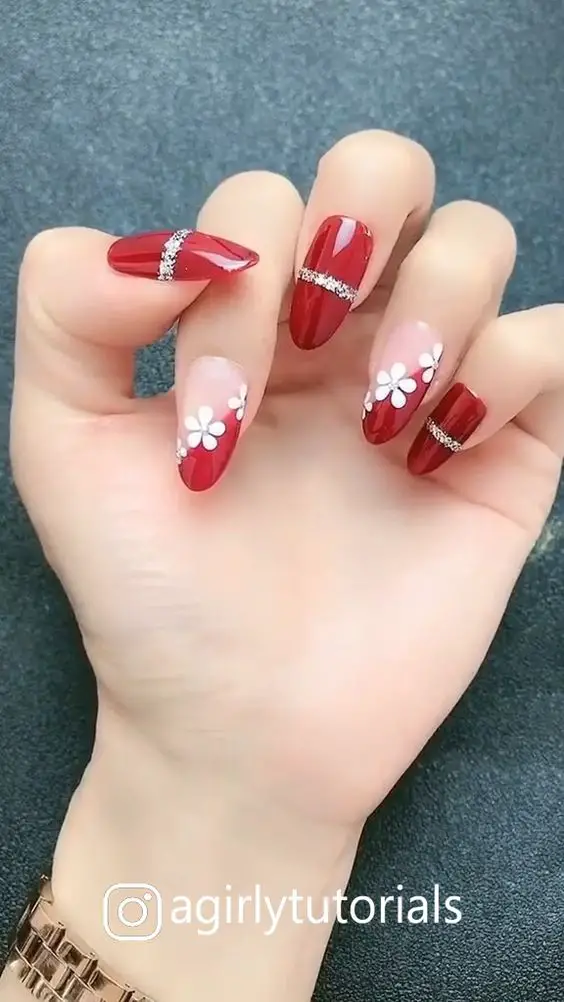 unhas vermelhas decoradas com listras prateadas e flores brancas