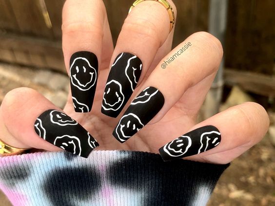 unhas pintadas de preto com desenhos brancos de carinhas felizes