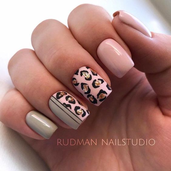 unhas pintadas com cor de rosa e cinza com estampas douradas