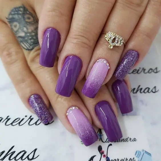 unhas roxas com glitter e pedras brilhantes