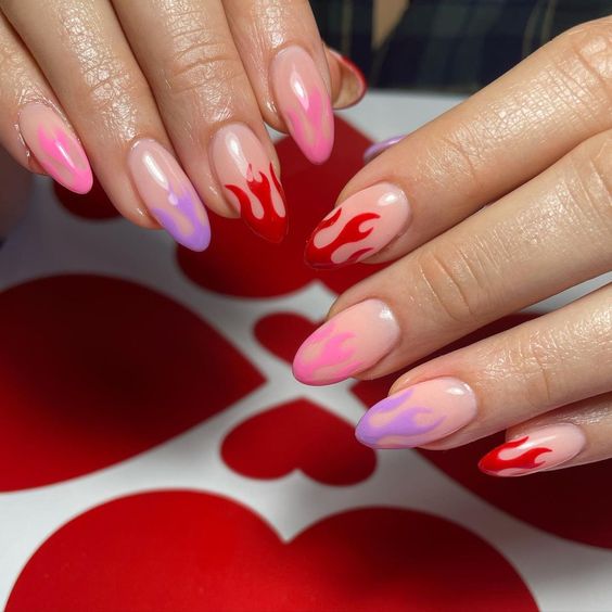 unhas decoradas com desenhos de chamas vermelhas e roxas