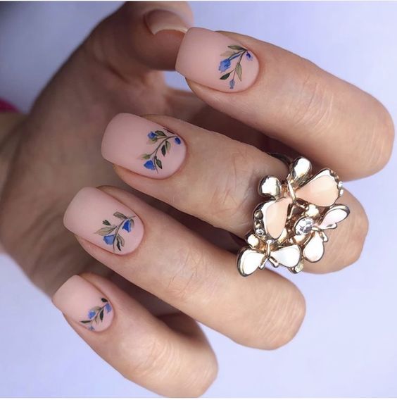 unhas com efeito matte decoradas com flores azuis