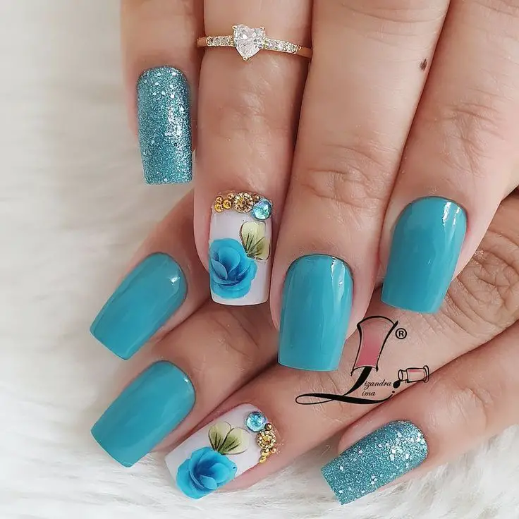 unhas decoradas com adesivos de joias azuis brilhantes