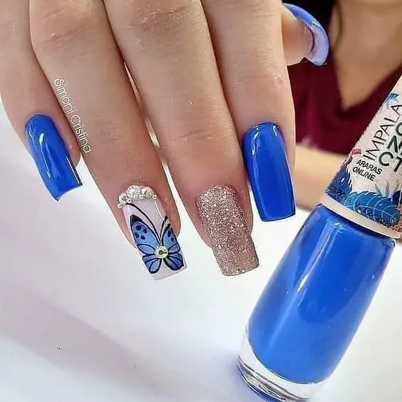 unhas com adesivos de borboleta e joias prateadas