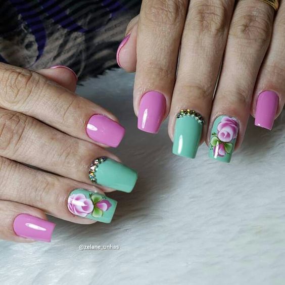 modelo de unhas rosa e verde claro com adesivos de flores