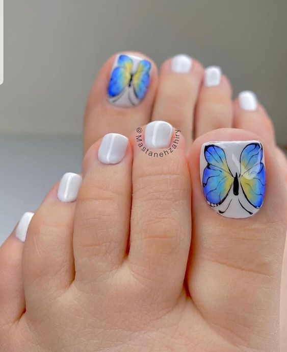 unhas decoradas dos pés com adesivos de borboletas azuis
