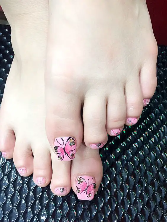 unhas dos pés com adesivo de borboleta