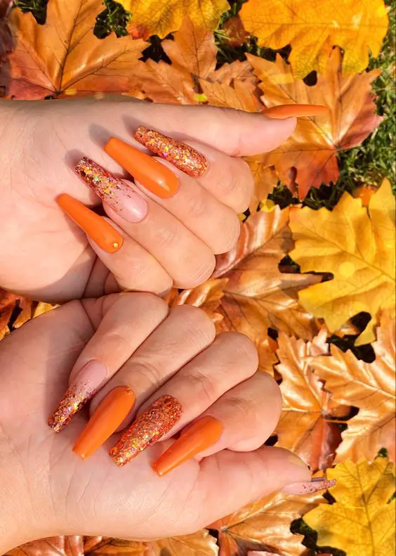 Foto de unhas decoradas laranjas com folhas de outono
