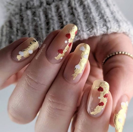 Exemplo de unhas decoradas com ouro e corações vermelhos