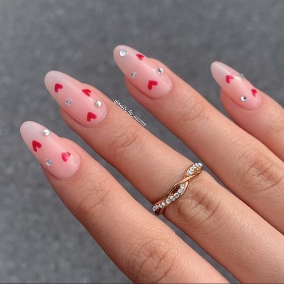 Design de unhas decoradas para o dia dos namorados com corações vermelhos e strass