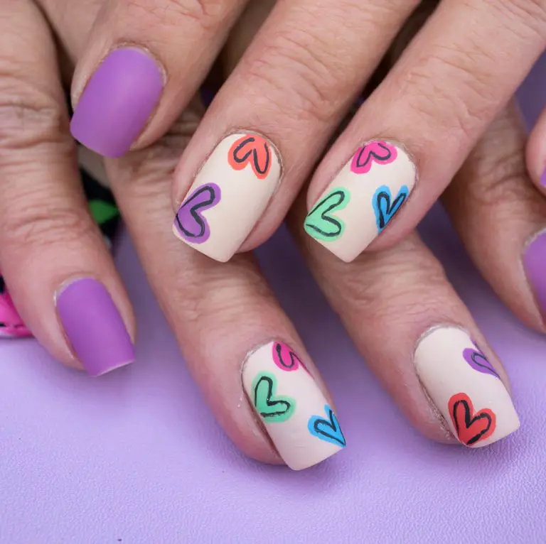 Modelo de unhas curtas roxas com desenhos de corações coloridos