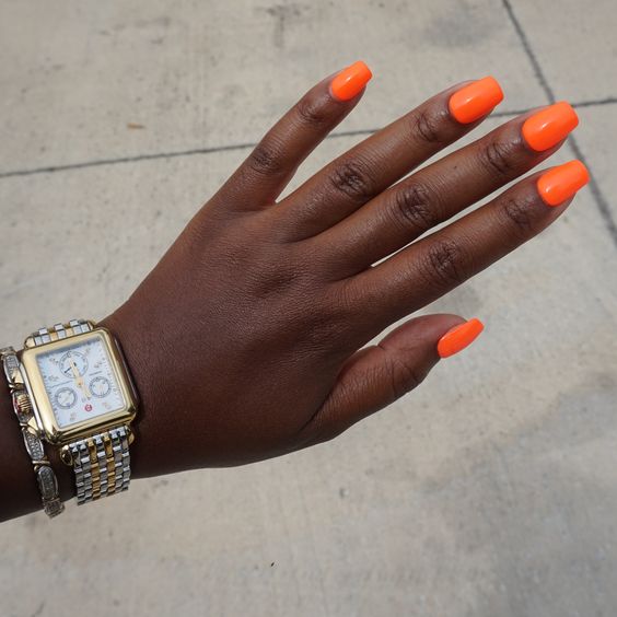 Mão com unhas laranja vivido
