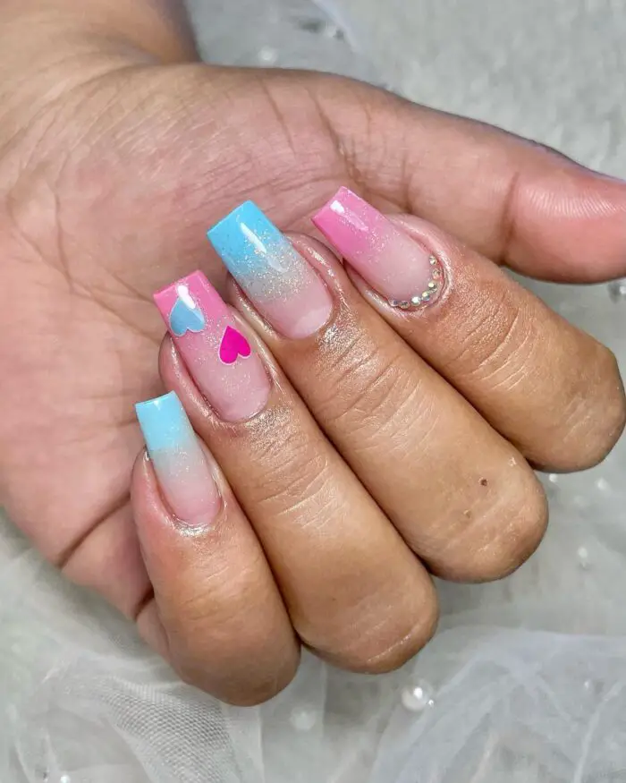 Esmaltação perfeita rosa e azul com glitter e desenhos de corações em uma das unhas