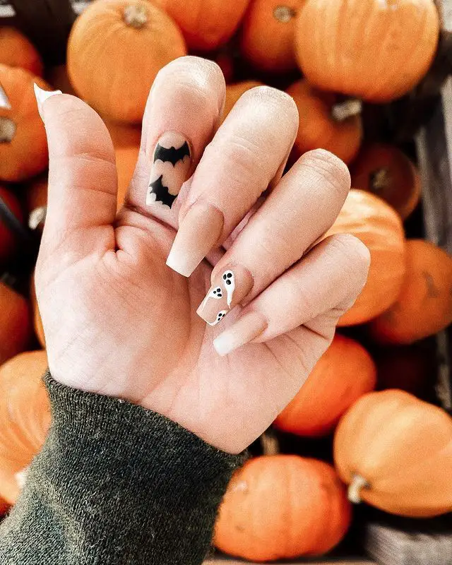 Delicadas unhas para halloween com aboboras atrás na foto