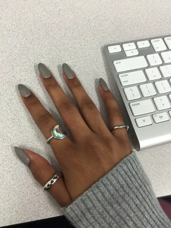 Foto de mão ao lado do teclado com as unhas decoradas para pele morena cinza