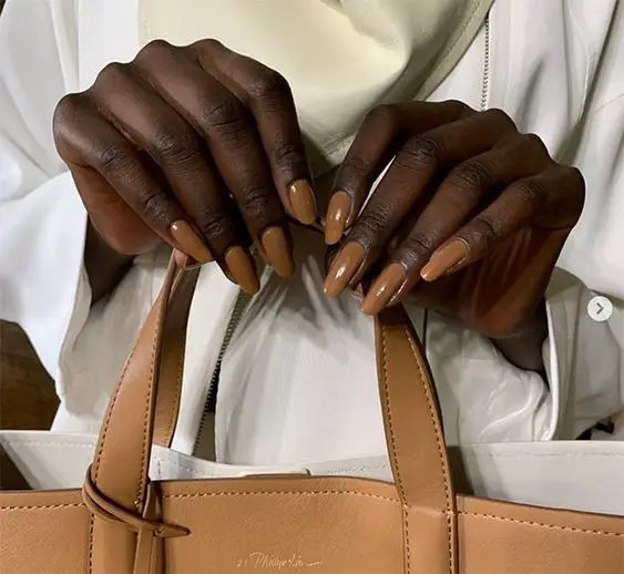 Foto de mãos com as unhas decoradas para pele morena caramelo segurado bolsa