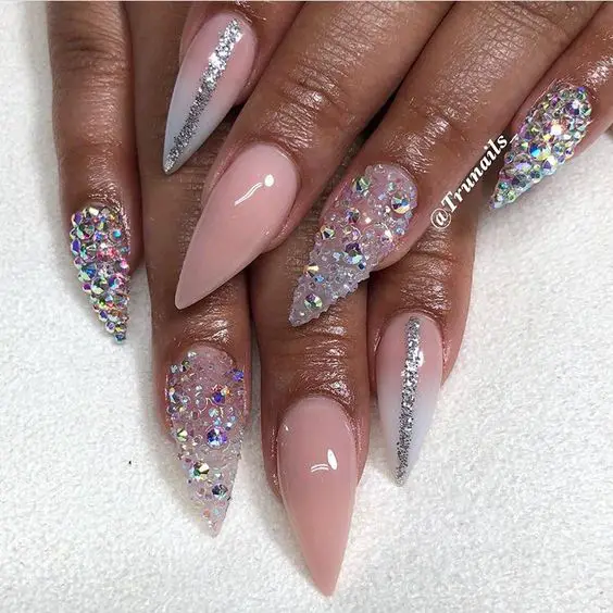 Foto de unhas stiletto com esmalte rosa claro e muita joias e brilho