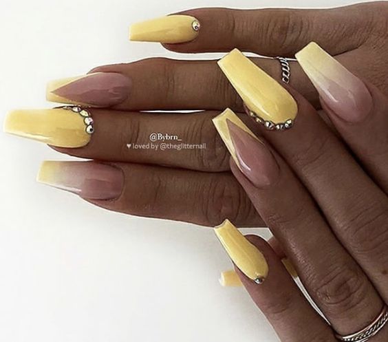 Design nas unhas compridas em tons de amarelo com joias