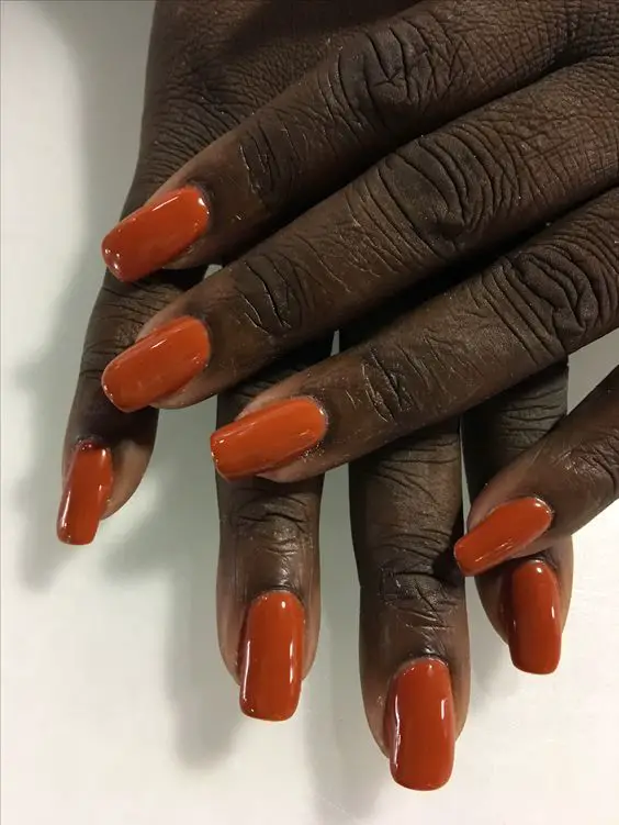 Pele morena com unhas laranjadas