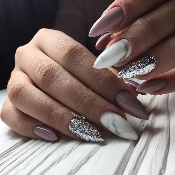 Modelo de unhas com esmaltação rosa, branco e glitter