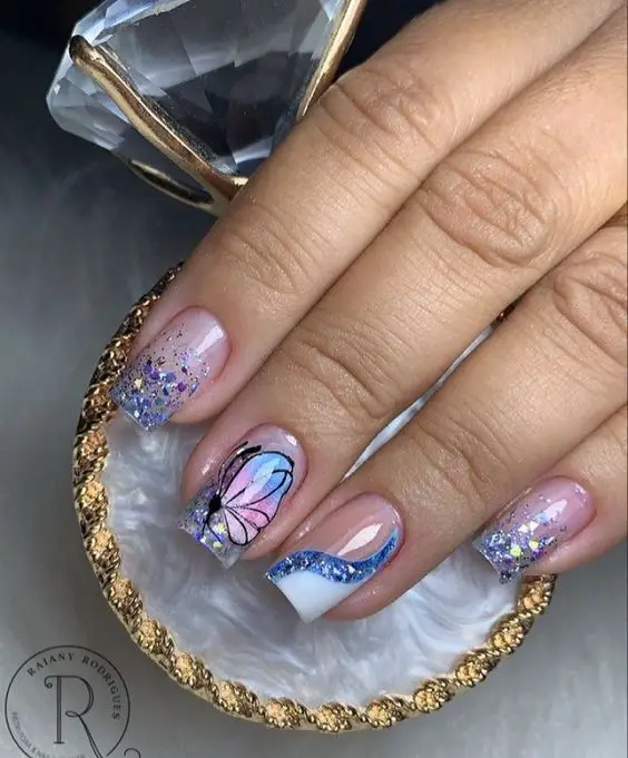 Modelo de unhas decoradas encapsuladas com borboletas e glitter