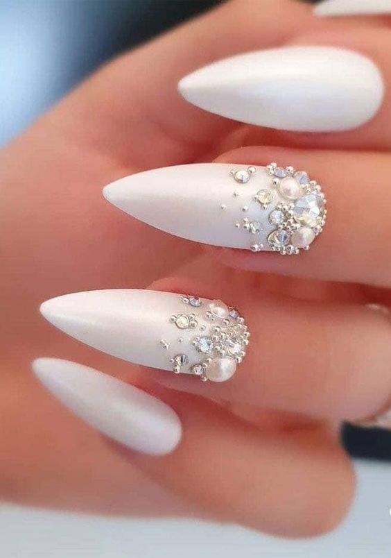 Formato de unhas stiletto brancas com joias e pérolas