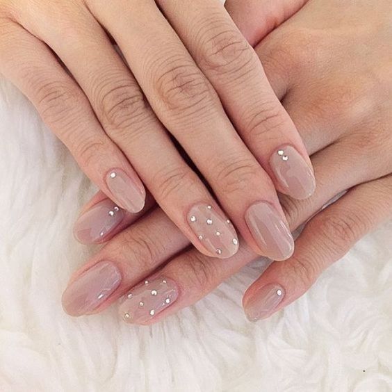 Modelo de unhas amendoadas nude com joias