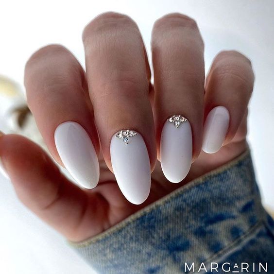 Unhas elegantes com esmalte branco decorado com joias