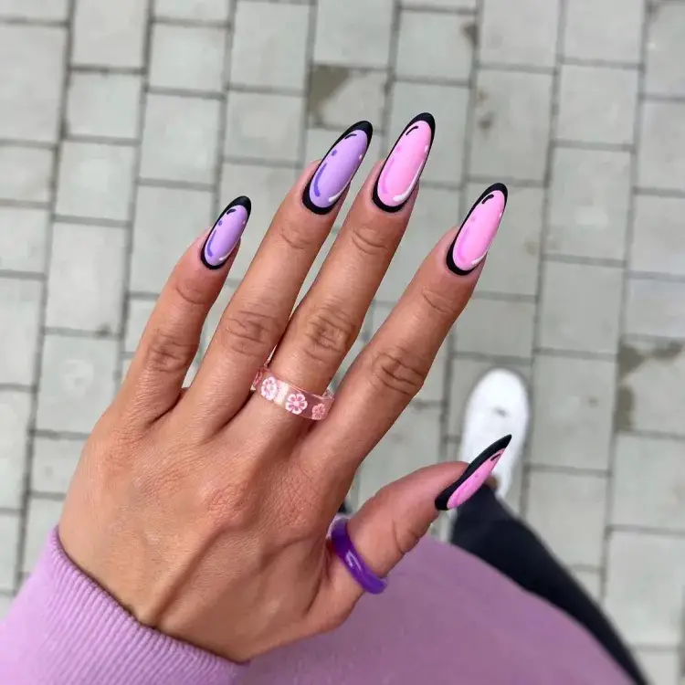 Imagem de unhas amendoadas compridas em tons de rosa e lilás, com bordas pretas imitando quadrinhos