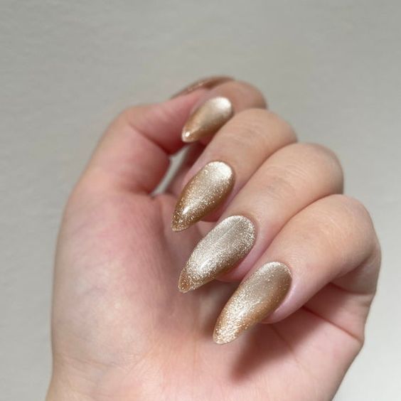 Foto de unhas pontudas com esmaltação magnética dourada