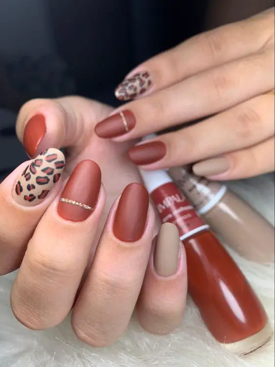 Inspirações de unhas em tons terrosos com nude e decoração oncinha