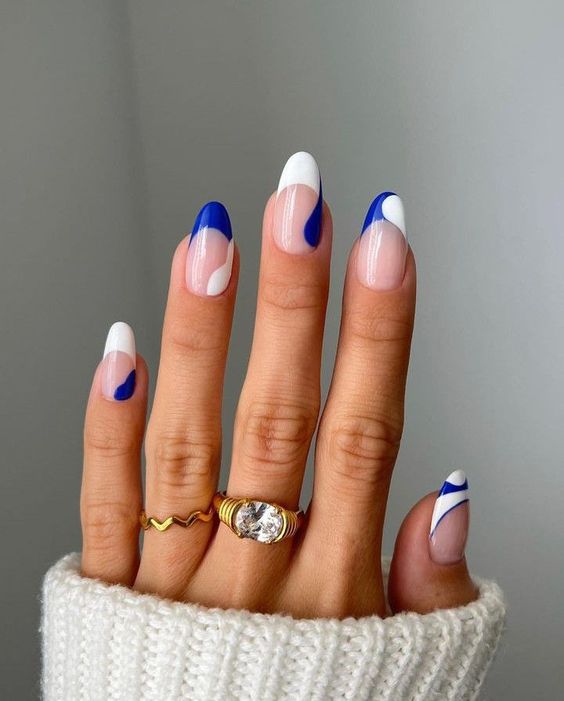 mão delicada exibindo unhas decoradas nas cores branco e azul marinho