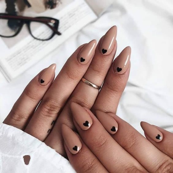 Exemplo de unhas nude pontiagudas com corações delicados pretos