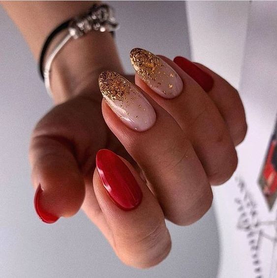 Modelo de unhas amendoadas vermelhas com glitter dourado