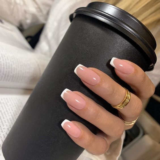 mãos com unhas decoradas segurando copo de café