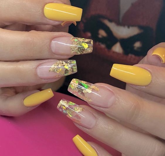 unhas amarelas transparentes com detalhes de folhas de ouro